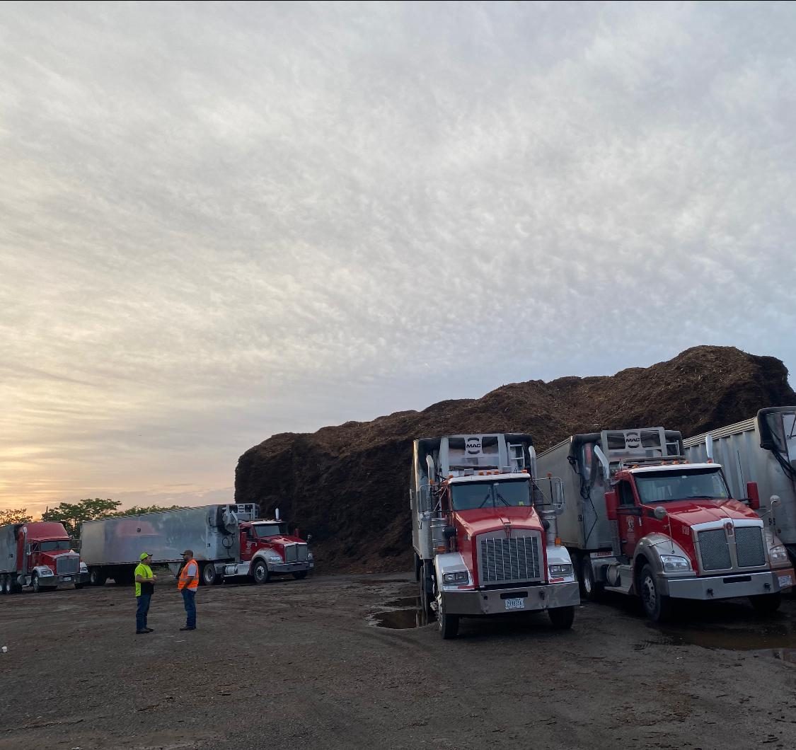 Pijuy trucks staged beside large mulch piles